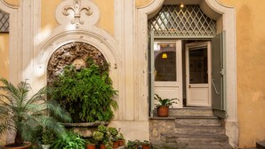 A building entrance with a stone staircase, a decorative archway, and potted plants. - Your Suite Rome (Rome)