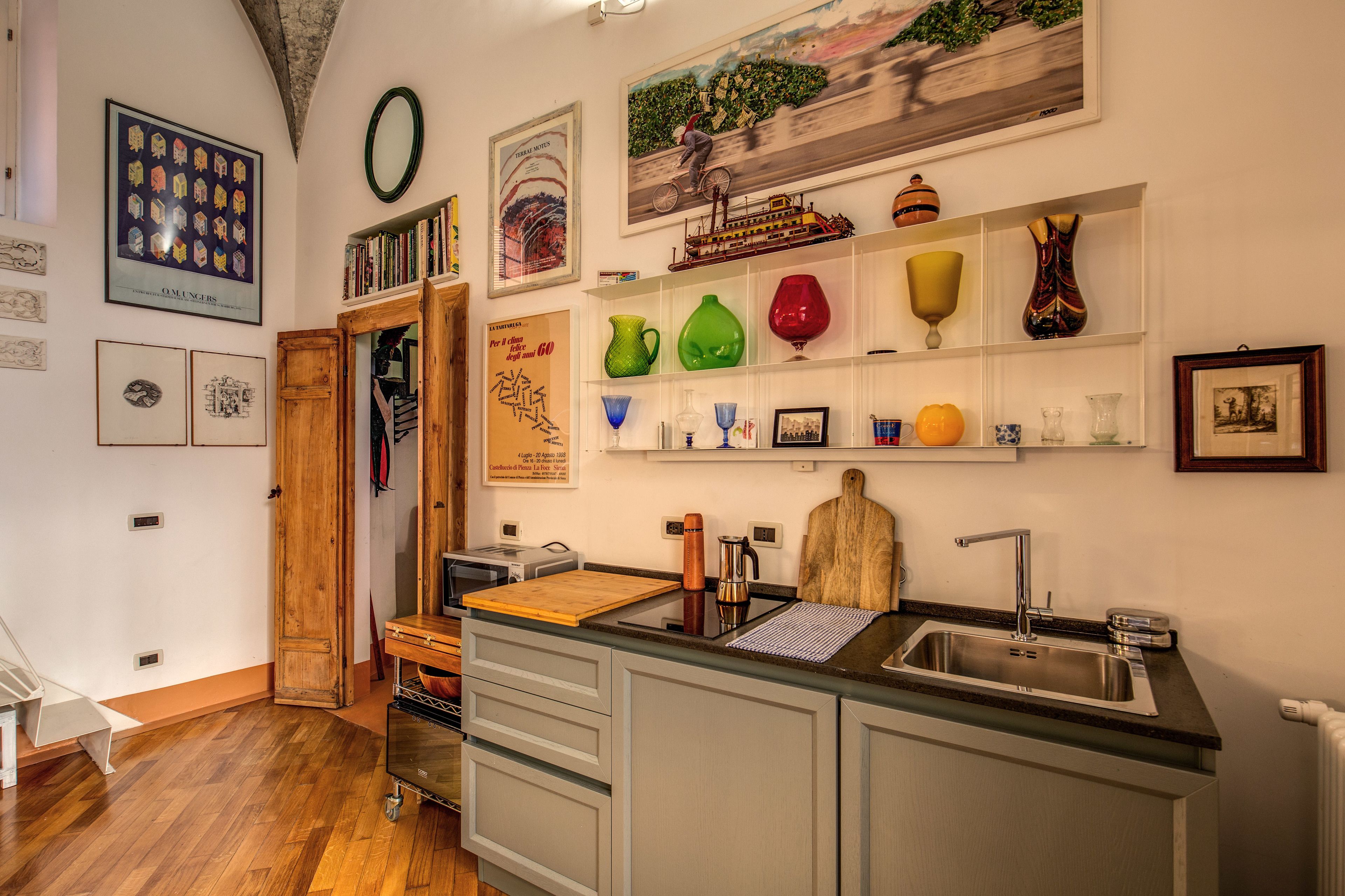 A kitchen with a wooden door, a sink, and a countertop with various items.