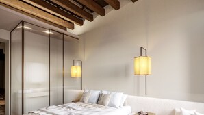 A modern bedroom with a large bed, two bedside lamps, a white sofa, and a wooden ceiling. - Your Suite Rome (Rome)