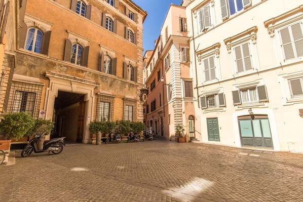 A cobblestone street with historic buildings, a scooter parked in front, and a door labeled "Parking."
