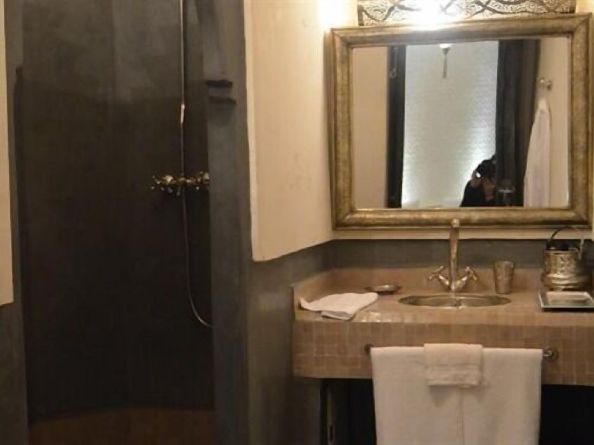 A bathroom with a dark door, a sink with a mirror, and a towel hanging on the wall.