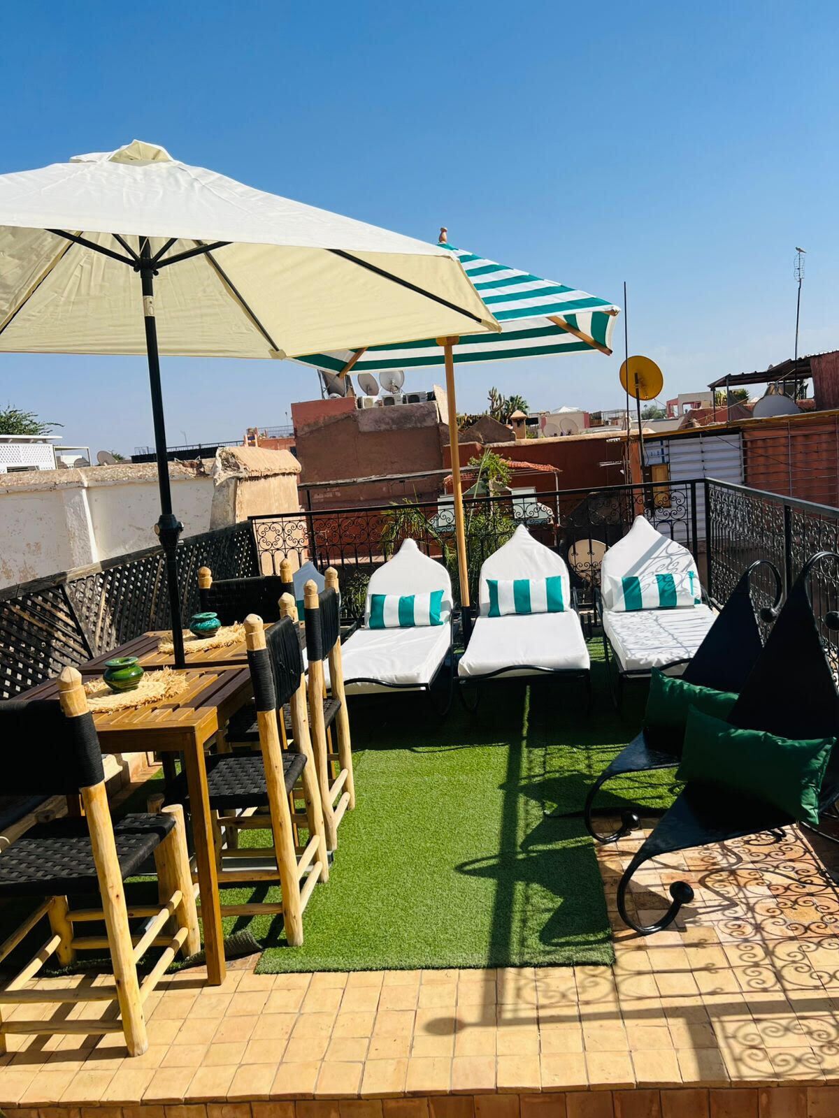Una terraza en la azotea con mesa, sillas y sillones de descanso, que ofrece vistas panorámicas de la ciudad.
