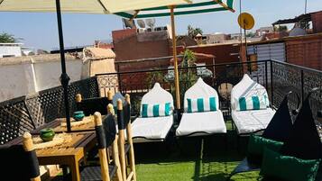 Una terraza en la azotea con mesa, sillas y sillones de descanso, que ofrece vistas panorámicas de la ciudad.