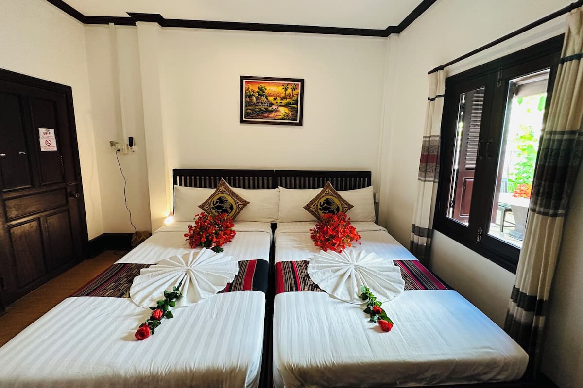 Una habitación de hotel con dos camas, un cuadro en la pared y una ventana con cortinas.
