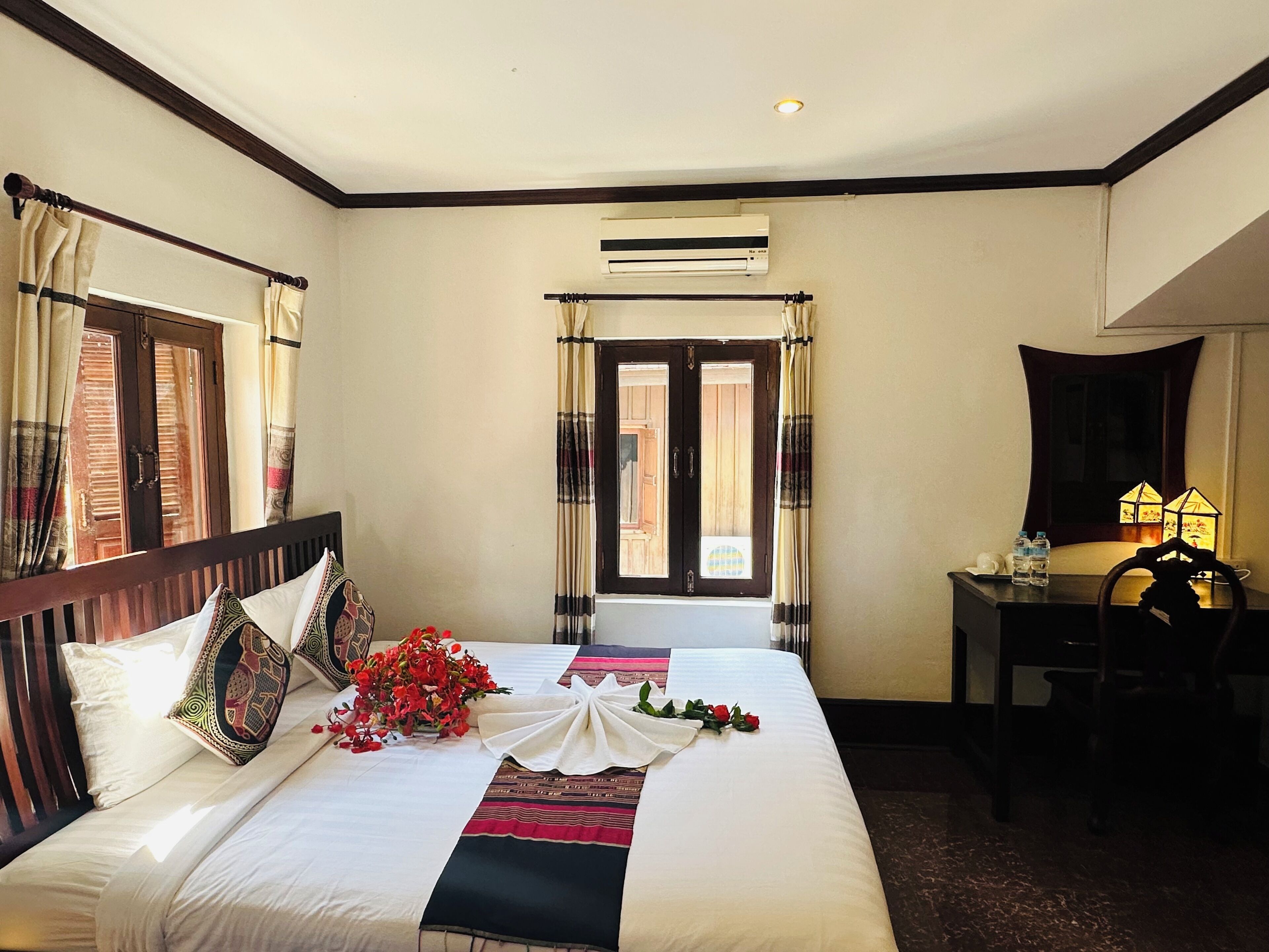 A hotel room with a large bed, a desk, and a window with curtains.