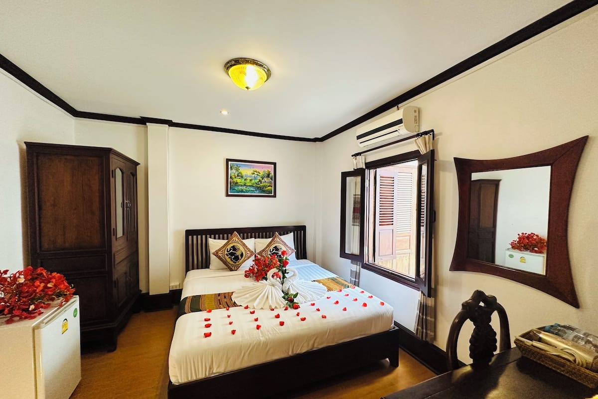 Habitación de hotel con cama, armario, ventana con vistas y un cuadro en la pared.