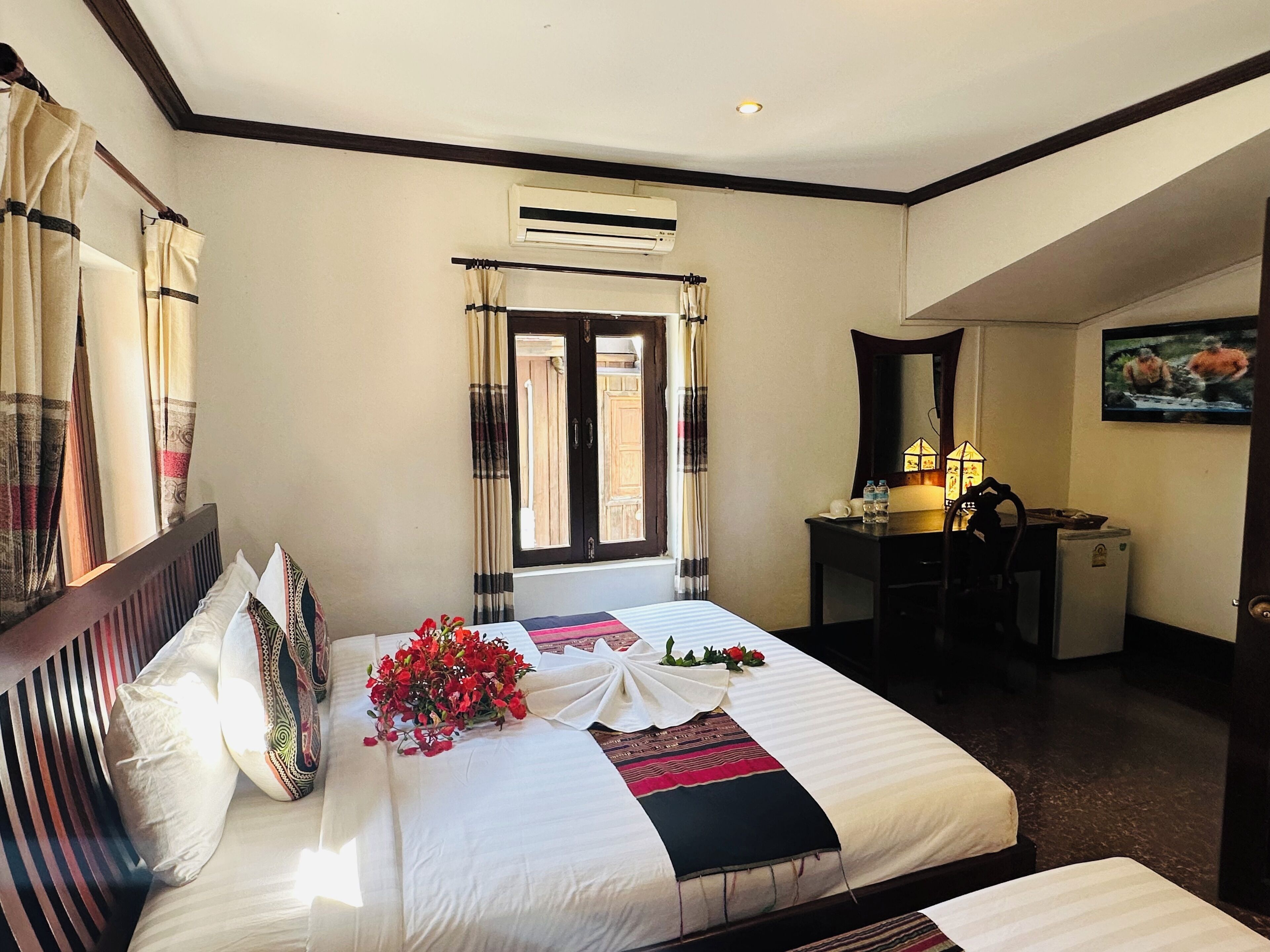 A hotel room with a bed, a desk, an air conditioning unit, and a television on the wall.