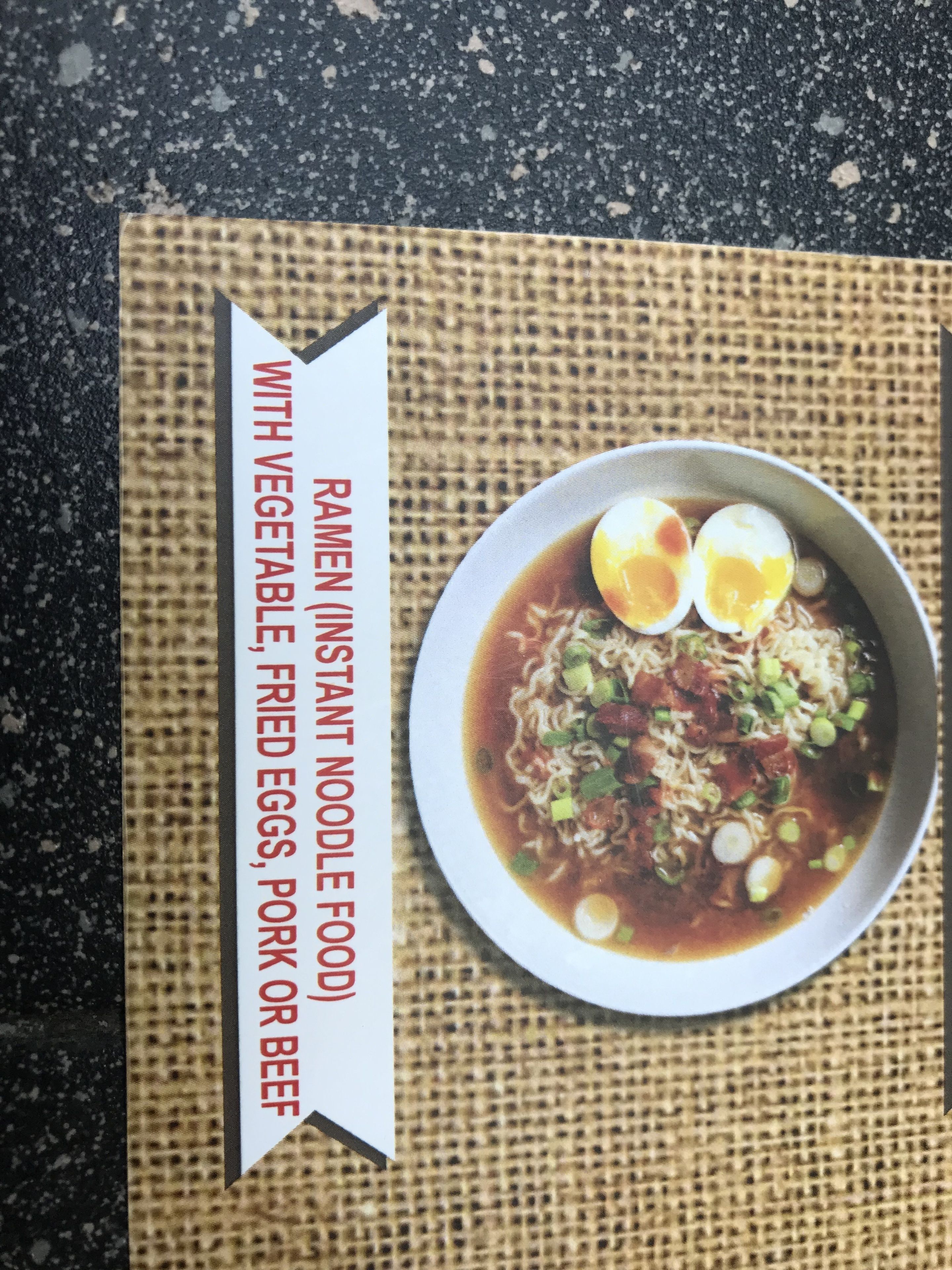 A bowl of ramen with eggs, vegetables, and meat, served on a textured mat.