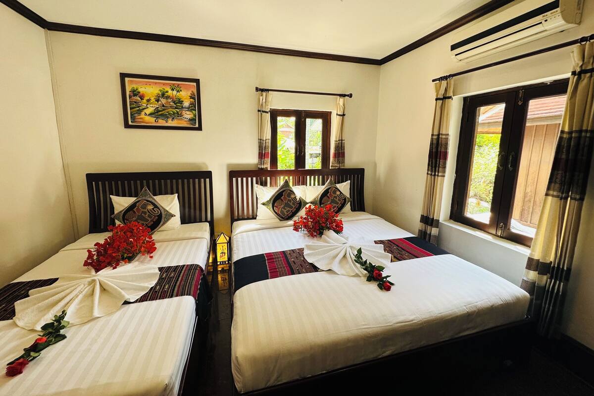 Una habitación de hotel con dos camas, cada una con un arreglo floral y un cuadro en la pared.