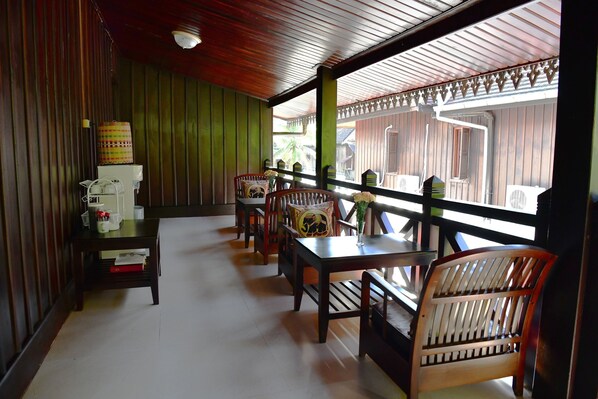 A covered outdoor seating area with wooden furniture and a view of the outside.