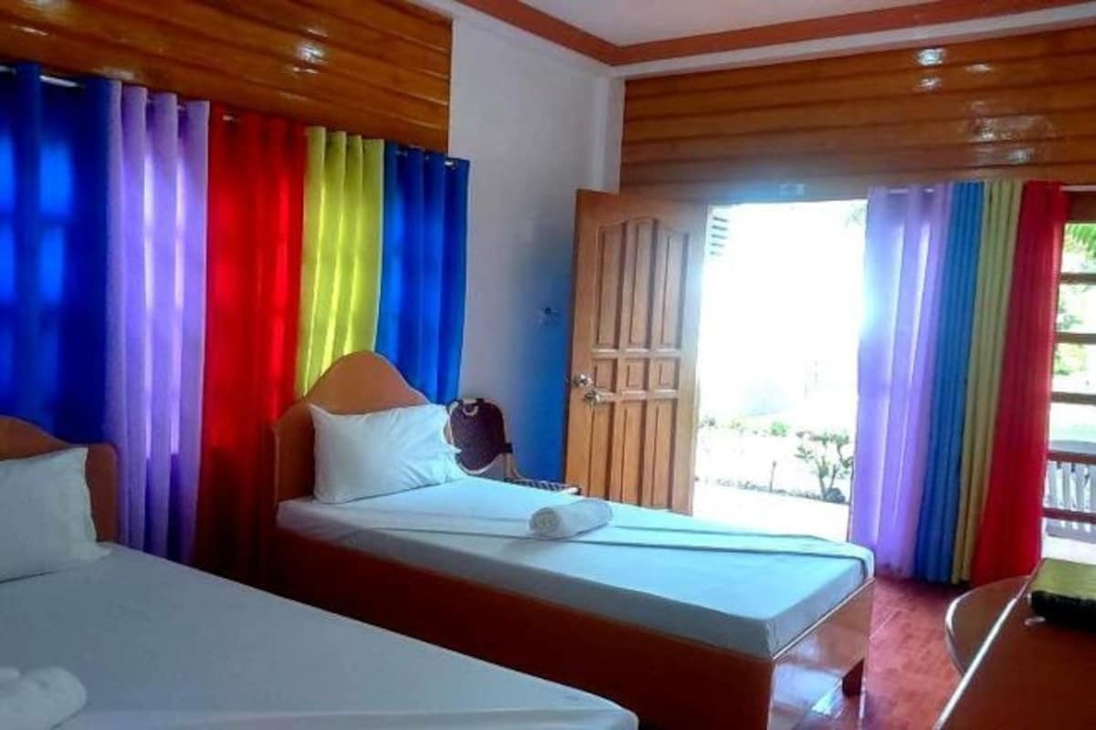 A hotel room with a bed, a wooden headboard, and colorful curtains.