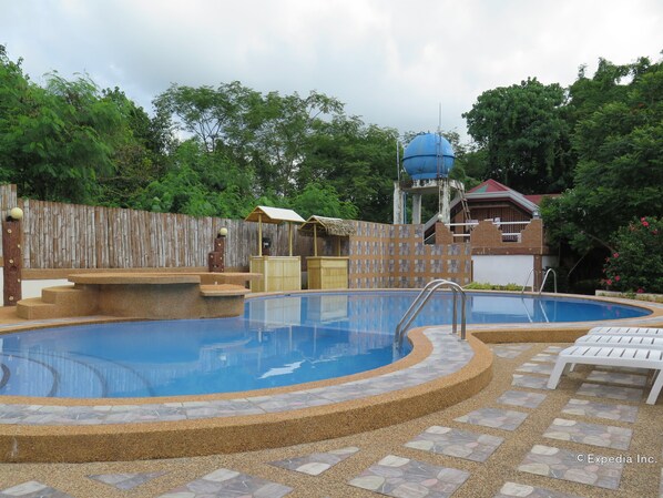A swimming pool with a stone border, a wooden fence, and a water tower in the background. -  Alona Hidden Dream Resort by SMS Hospitality (Panglao)