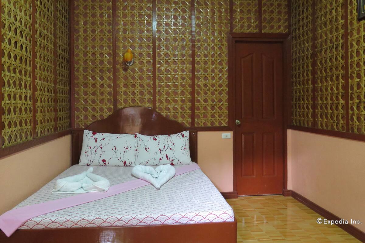 A hotel room with a bed, a wooden door, and patterned walls.