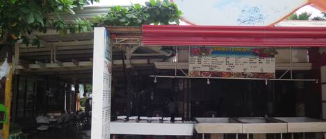 A restaurant with a sign reading "Hidden Dream Grill & Restaurant" and a menu board listing seafood dishes.