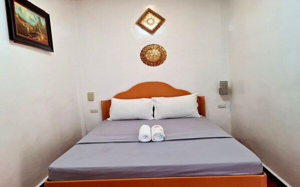 Una cama individual con cabecera de madera, dos almohadas y un edredón impecable.