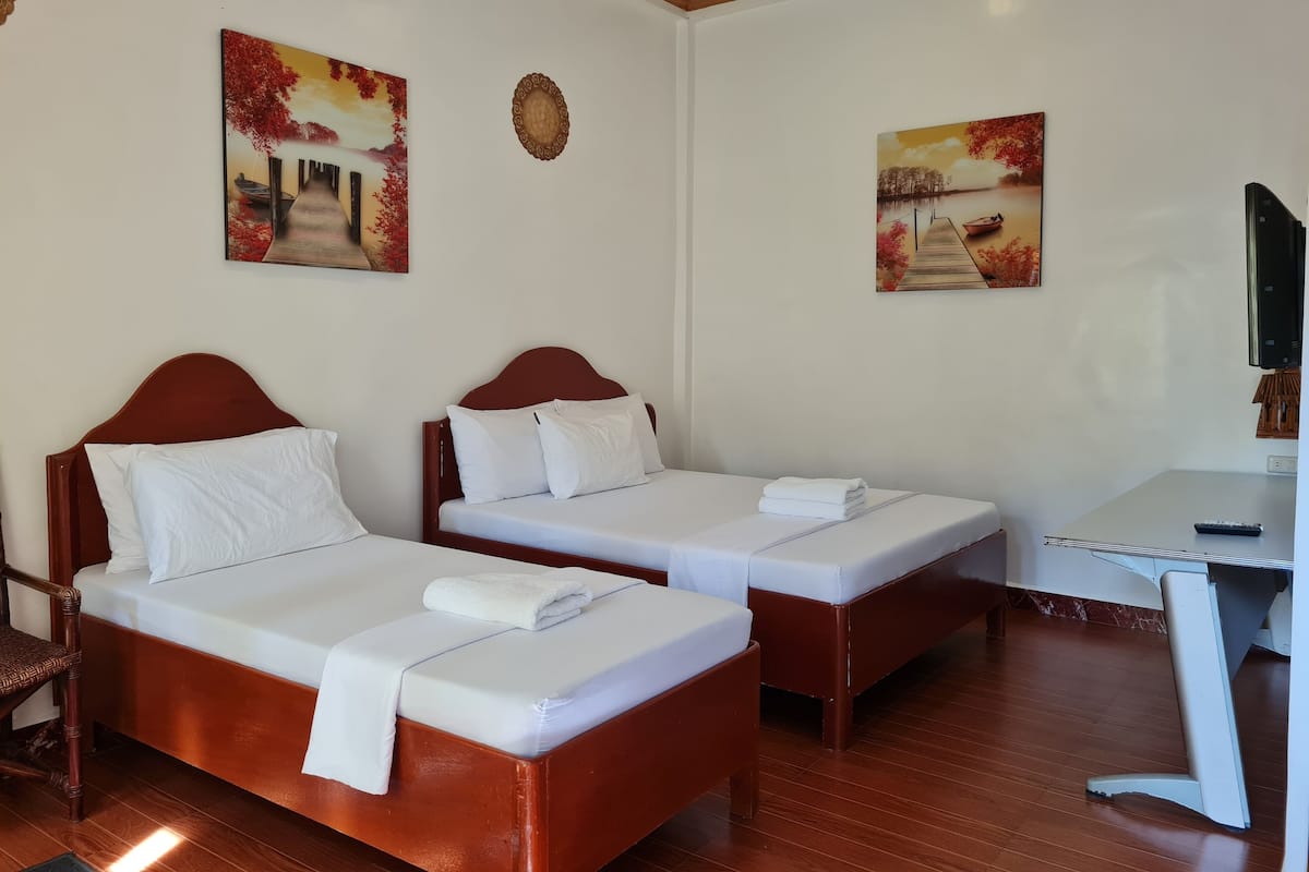 A hotel room with two beds, a desk, and a TV.