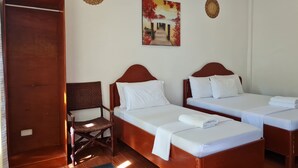 Habitación de hotel con dos camas individuales, una silla de madera, una puerta y dos adornos en la pared.