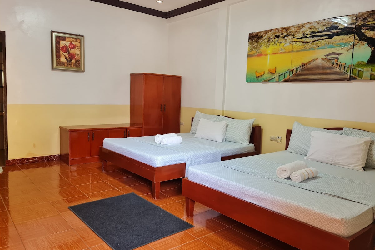 A hotel room with two beds, a wardrobe, a painting, and a wooden floor.