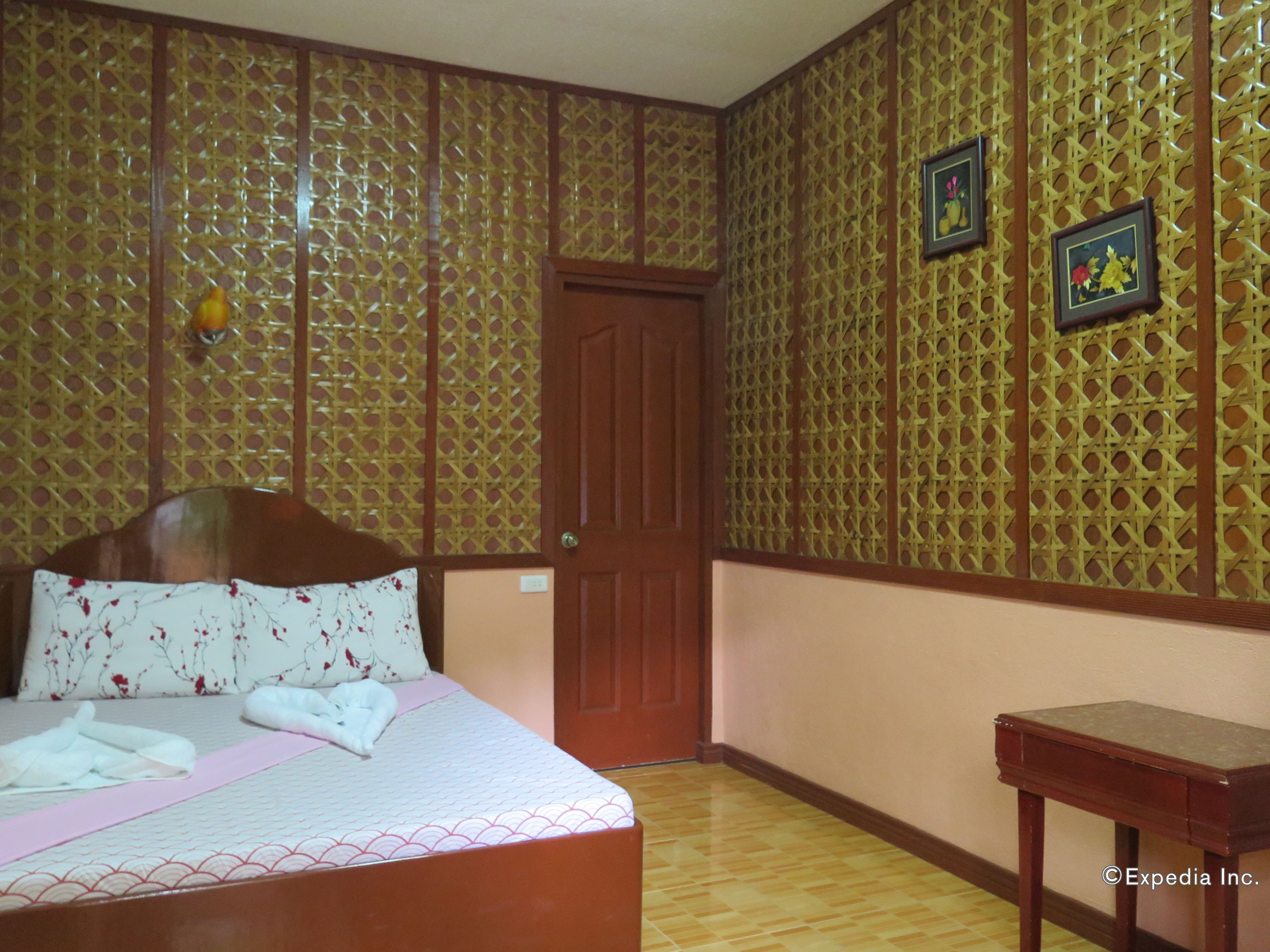 Una habitación con una cama, una puerta de madera y una mesita.