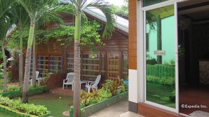 Un edificio con un cartel que dice “INFORMACIÓN” y un letrero de “Bienvenida”. Hay palmeras y un jardín con plantas y un banco.