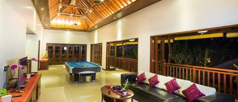 A spacious indoor area with a pool table, a sofa, and a dining table.
