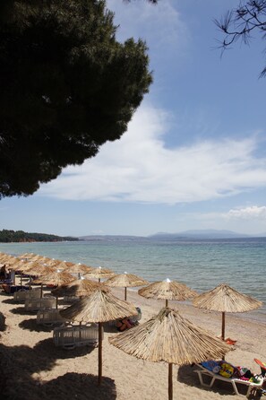 A beach with straw umbrellas and lounge chairs. - Porto Matina Hotel (Polygyros)
