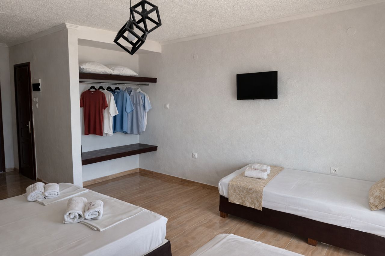 A hotel room with two beds, a wardrobe, a flat-screen TV, and towels on the beds.