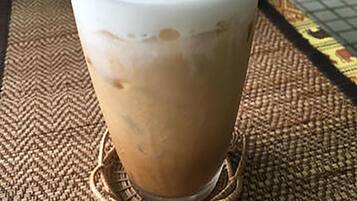 Un got de cafè helat amb nata i un pols de cacao sobre un suport trenat.