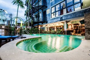A pool area with lounge chairs, a staircase, and a building with large windows and a balcony. - Chedi Home Chiang Mai (Chiang Mai)