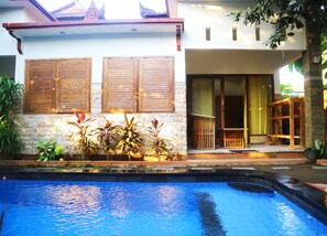 A house with a swimming pool, wooden shutters, and a stone wall. - Susan Bungalow (Gili Air)