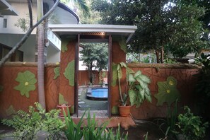 A courtyard with a pool, potted plants, and a decorative wall with leaf patterns. - Susan Bungalow (Gili Air)