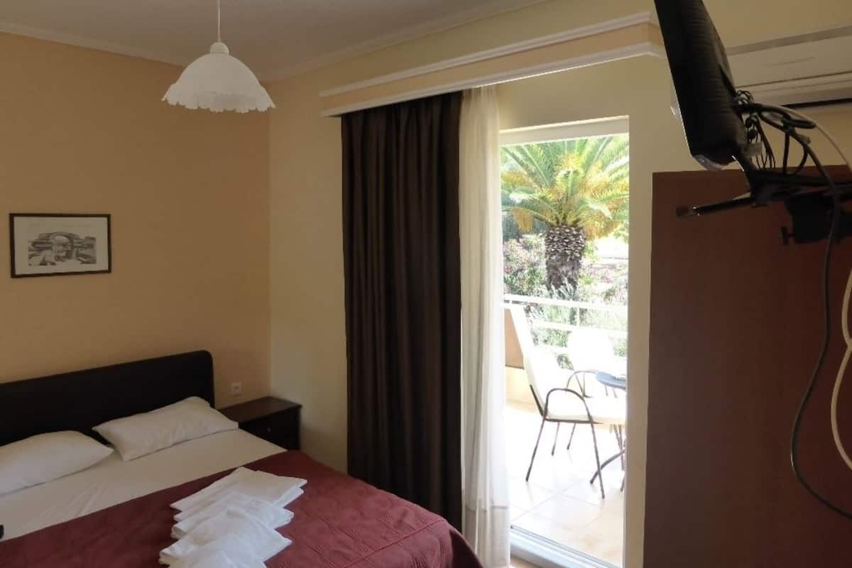 Habitación de hotel con cama, escritorio, silla, televisor y ventana con vistas al exterior.