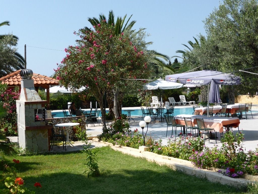 A poolside area with outdoor seating and umbrellas, a stone structure, and a garden with flowers.