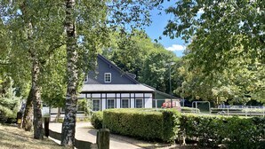 A traditional building with a dark roof and white trim, surrounded by well-maintained hedges and trees. - Hotel Gut Moschenhof (Düsseldorf)
