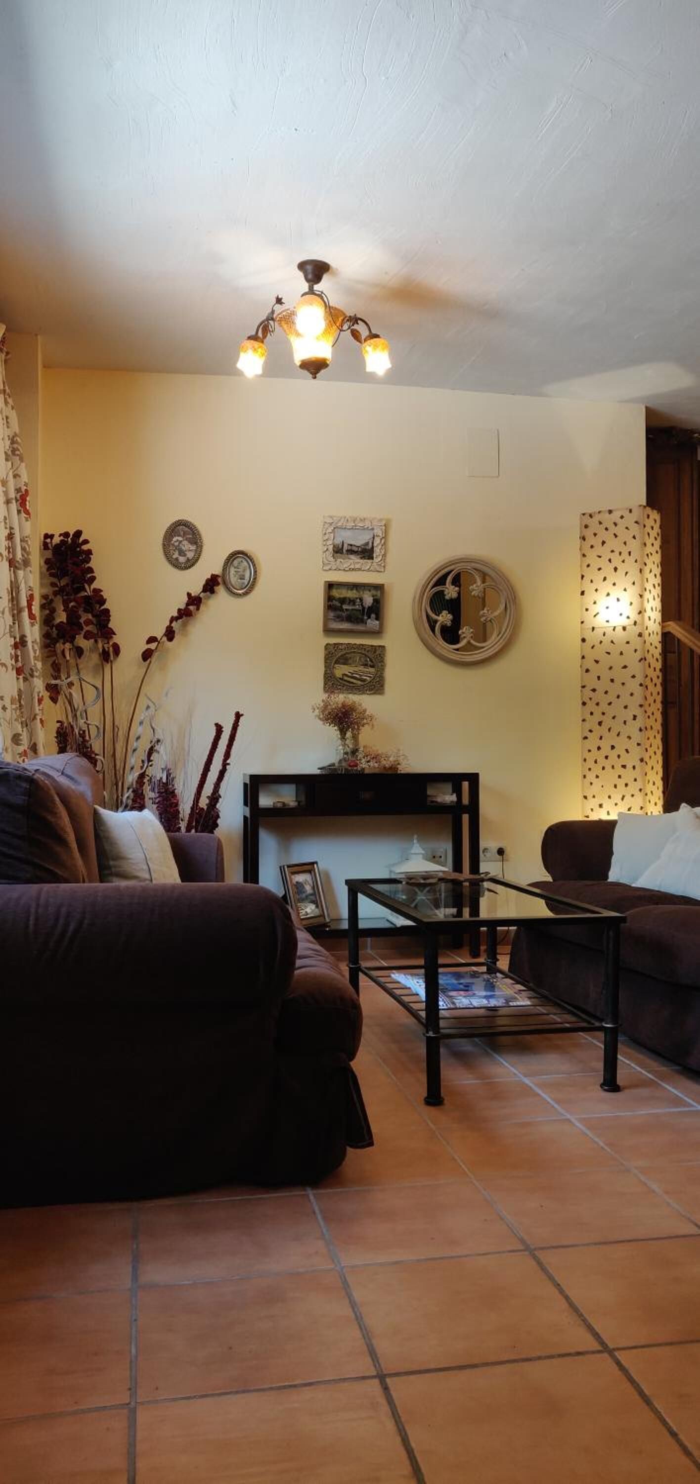 A living room with two sofas, a coffee table, and a fireplace. There are wall decorations and a ceiling light fixture.