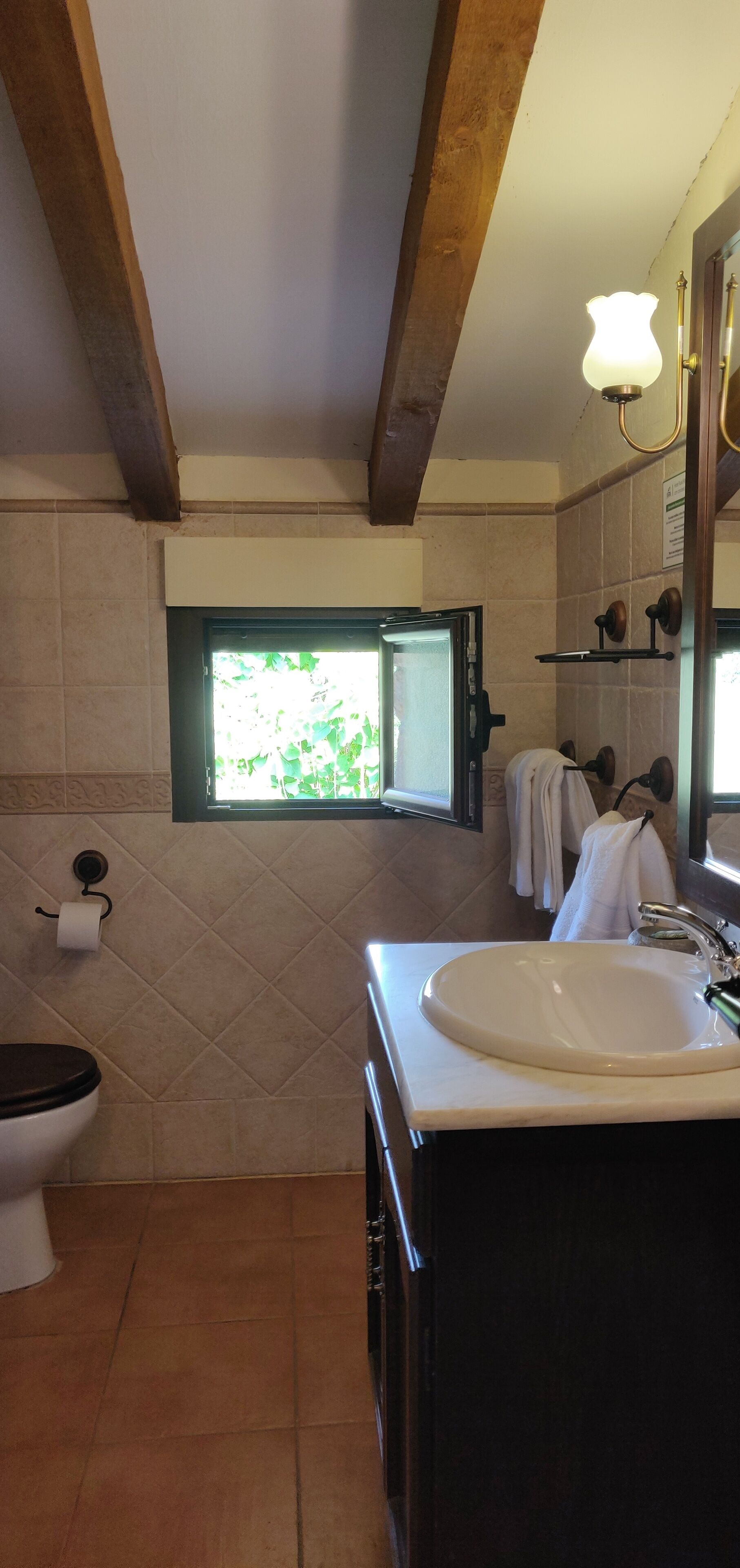 Un baño con inodoro, lavamanos y ventana.