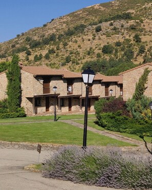 A stone building with a courtyard, a street lamp, and a mountain in the background.