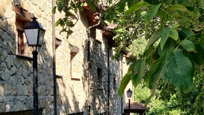 A stone building with a traditional design, featuring a stone facade, multiple windows, and a small covered area with a roof. - Hotel Ribera del Corneja (Navacepedilla de Corneja)