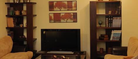 A living room with a TV, sofas, a coffee table, and decorative items.