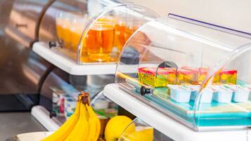 A self-service breakfast station with a variety of food items, including fruits and packaged goods.