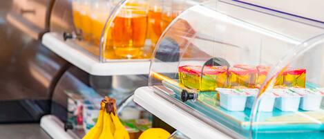 A self-service breakfast station with a variety of food items, including fruits and packaged goods.