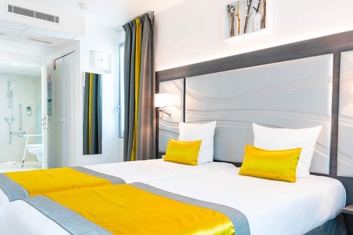 Una habitación de hotel con una cama grande, una mesita de noche y una lámpara de pared.