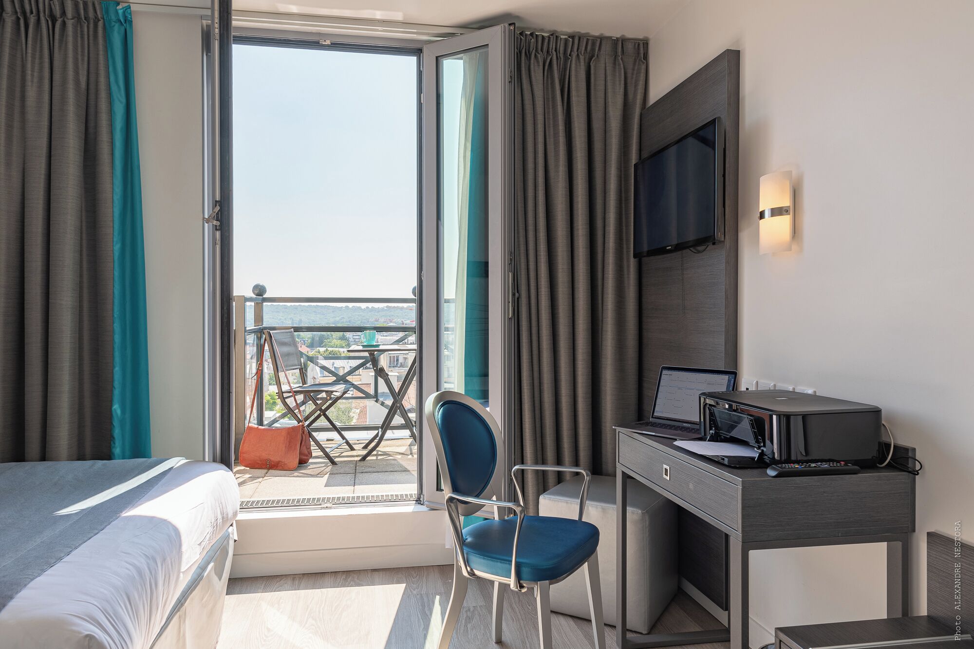 Une chambre d’hôtel équipée d’un lit, d’un bureau avec un ordinateur portable, d’une chaise et d’un téléviseur.