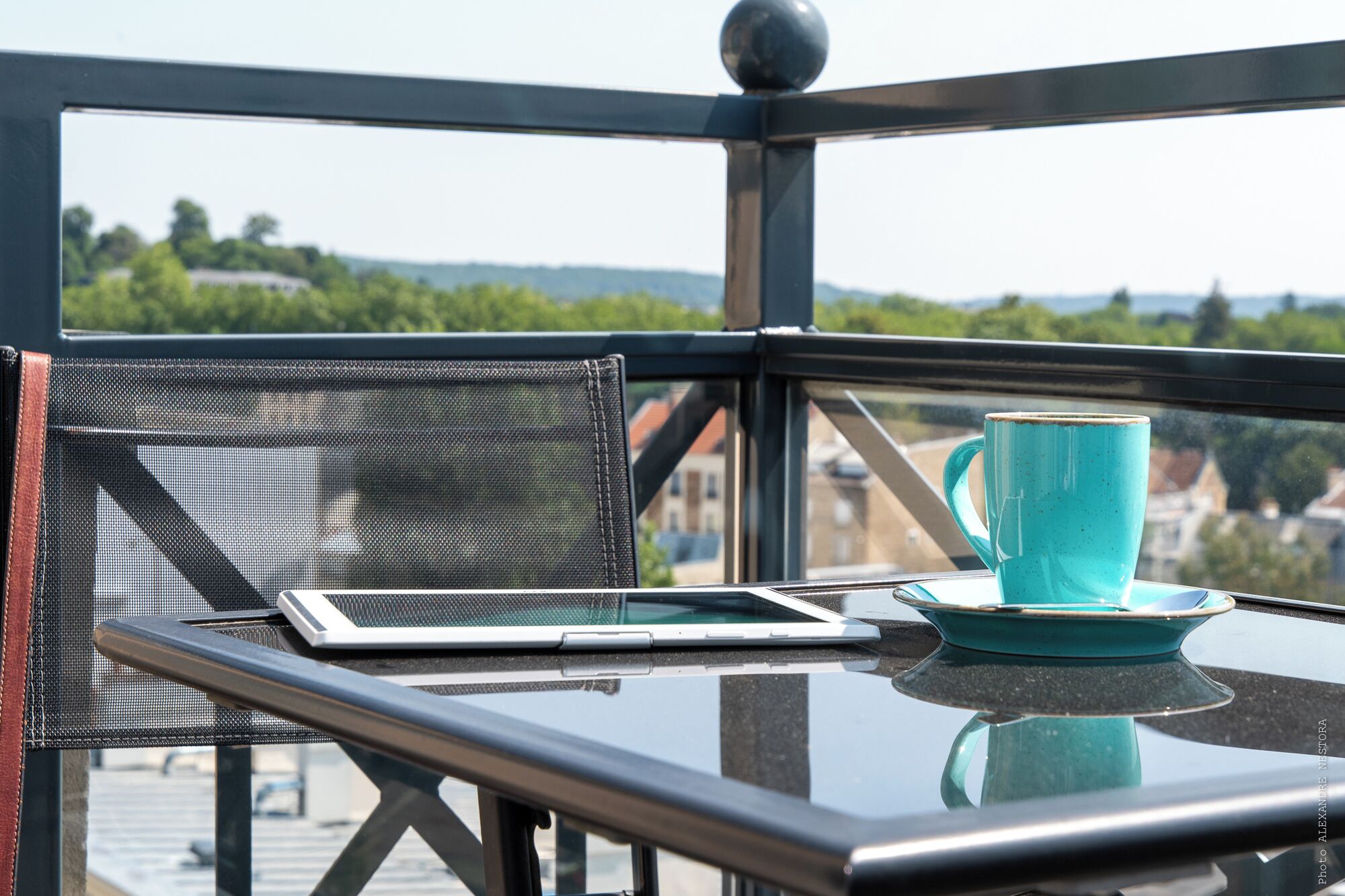 A balcony with a table, a blue mug, and a tablet.
