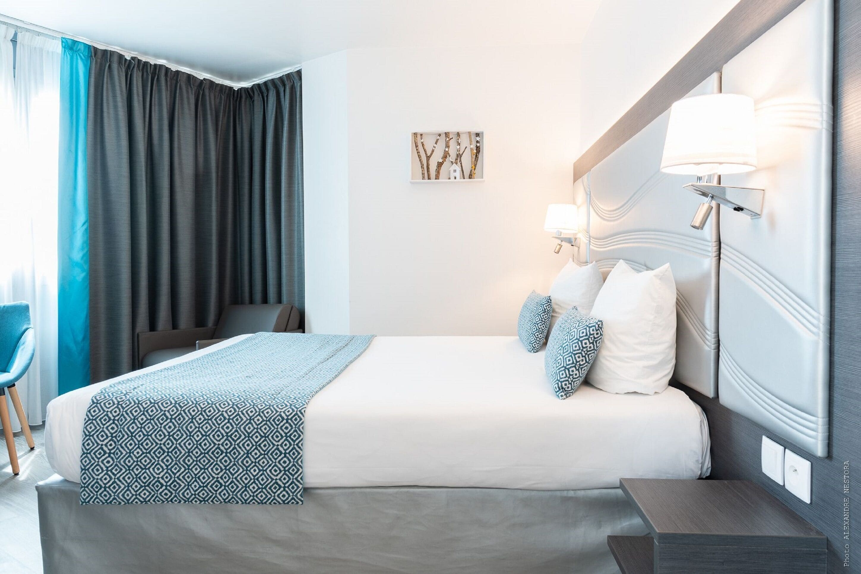Ein Hotelzimmer mit Bett, Nachttisch, Lampe und Stuhl.