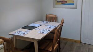 A dining area with a table set for two, a framed picture on the wall, and a skylight above. - Apple Loft (Alford)