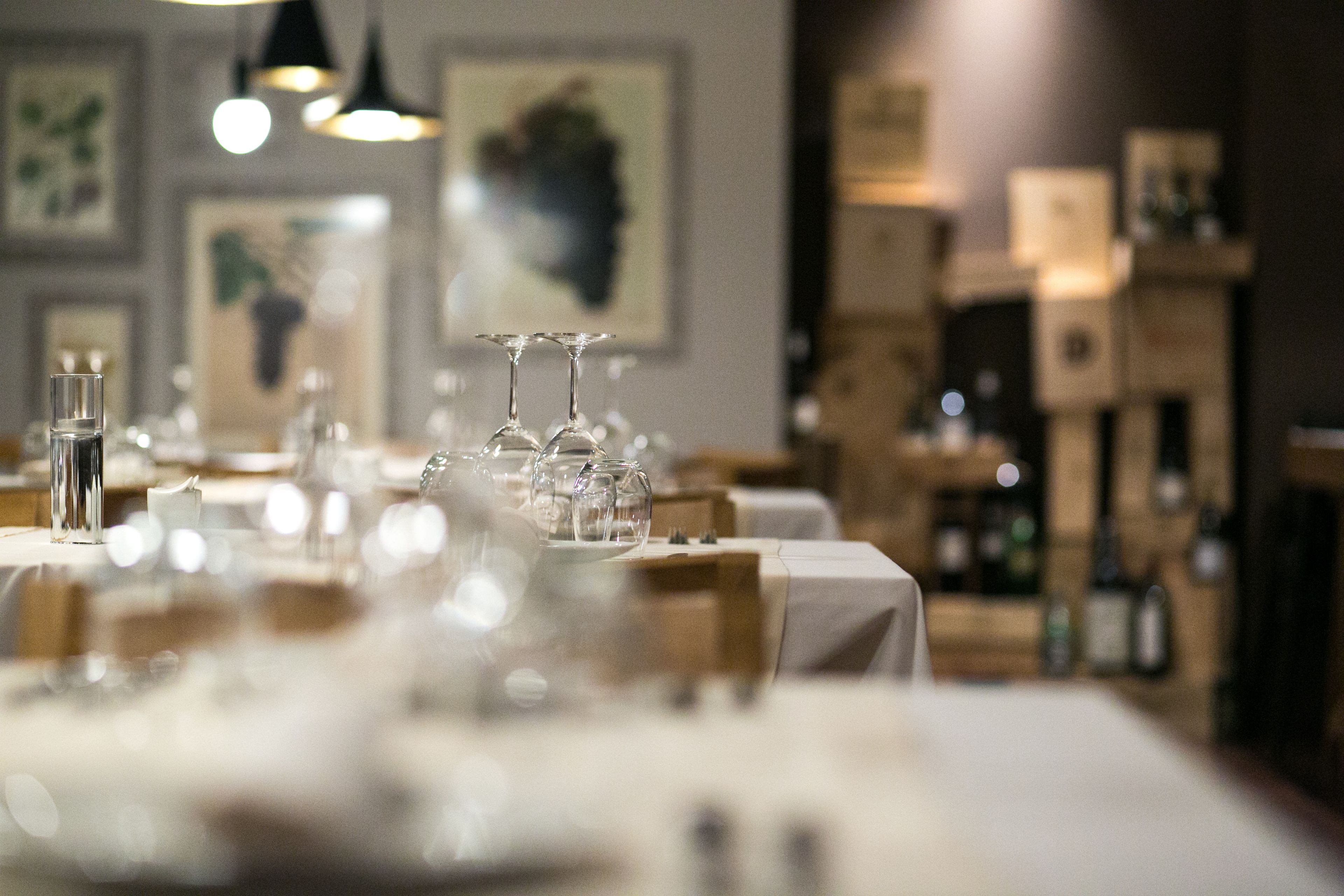 A restaurant with tables set for dining, glasses, and bottles on the tables.