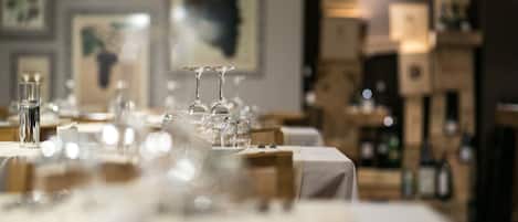 Un restaurant où les tables sont dressées pour le service, avec des verres et des bouteilles posés dessus.