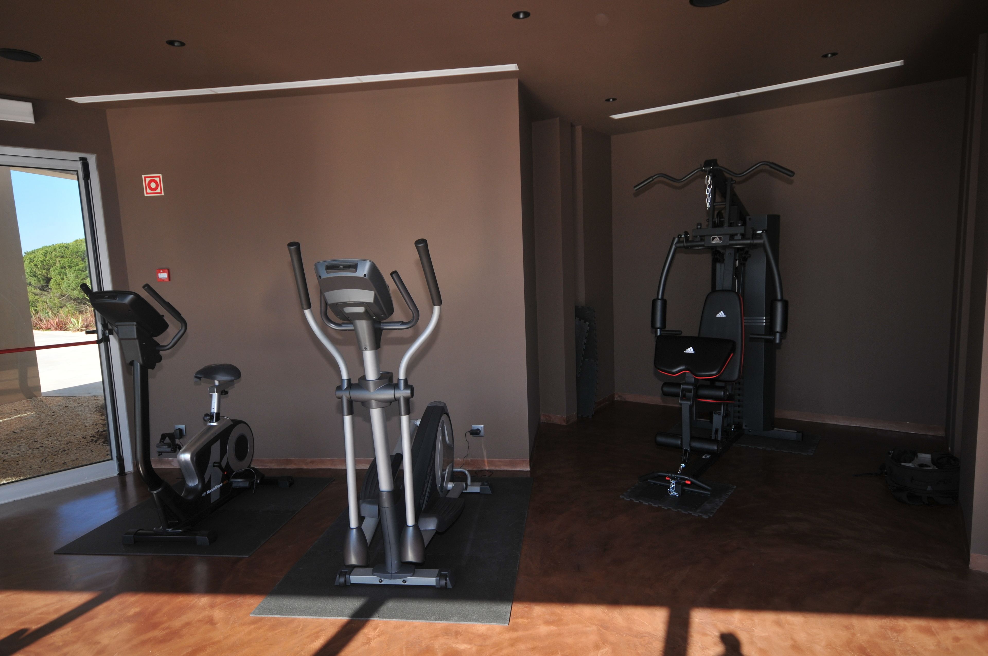 Une salle de sport équipée de machines de cardio, d’un vélo d’appartement et d’une machine de musculation.