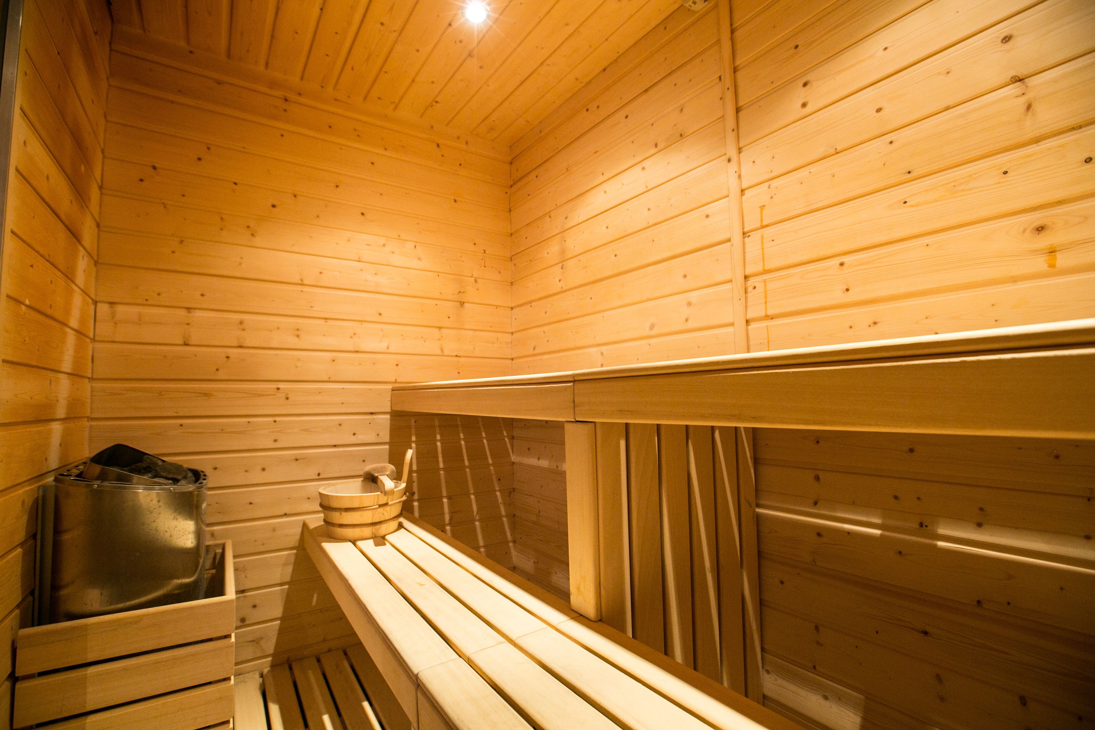 Un sauna en bois, doté de bancs et d’un récipient en métal, probablement destiné à contenir de l’eau ou de la vapeur.